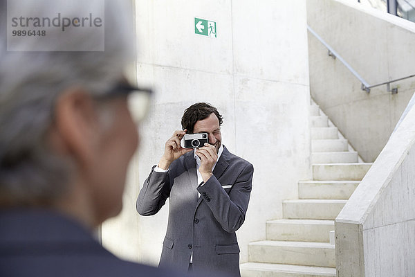 Geschäftsmann fotografiert seine Kollegin mit Kamera