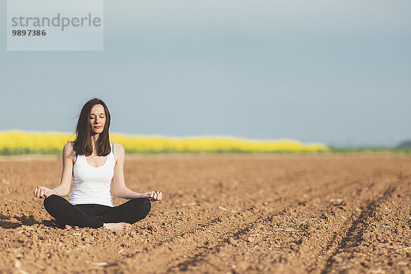 Frau meditiert auf einem Feld