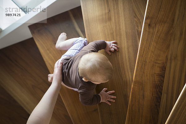 Mutters Hand hilft dem kleinen Mädchen beim Treppensteigen