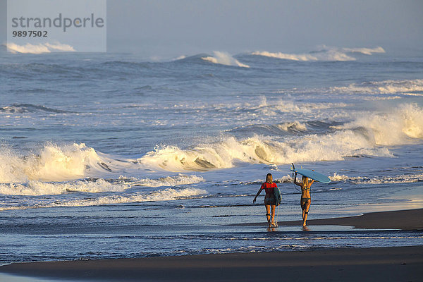 Indonesien  Bali  zwei Frauen mit Surfbrettern am Meer