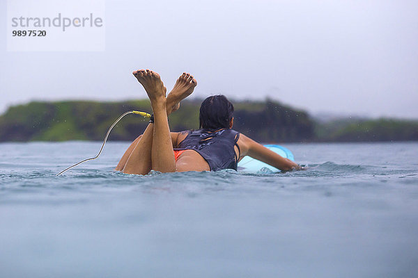 Indonesien  Lombok Island  Frau entspannt auf dem Surfbrett im Wasser