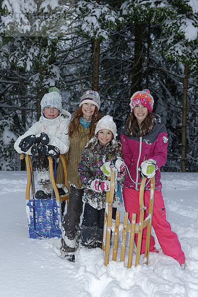 Kinder im Schnee stehend mit Schlitten