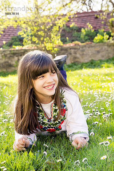 Porträt eines lächelnden Mädchens auf einer Wiese liegend