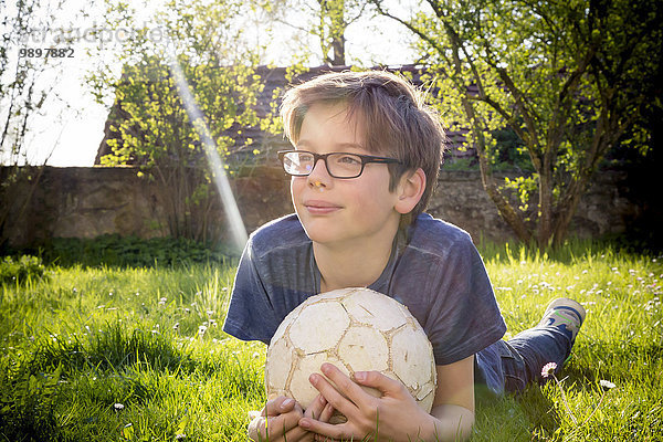 Porträt eines Jungen auf einer Wiese mit Fußball