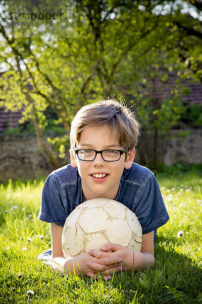 Porträt eines Jungen auf einer Wiese mit Fußball