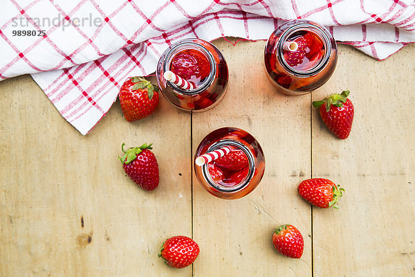 Drei Glasflaschen hausgemachte Erdbeerlimonade