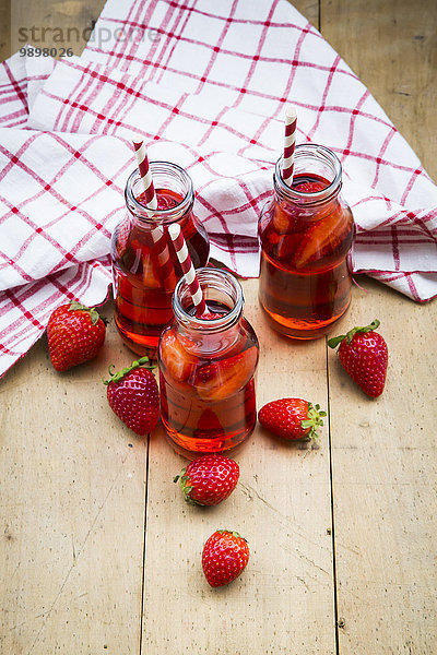 Drei Glasflaschen hausgemachte Erdbeerlimonade