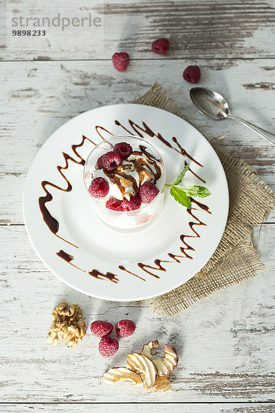 Dessert im Glas mit Himbeeren  Quark  Joghurt  Trockenapfel  Mandelsplittern und Schokoladensauce