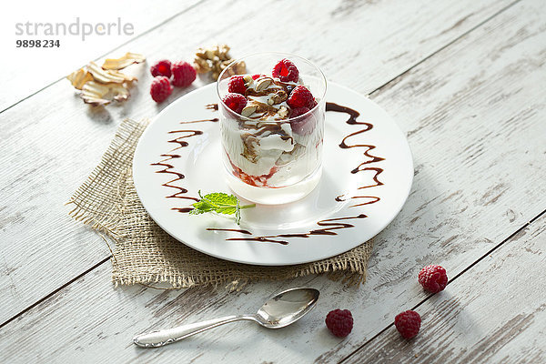 Dessert im Glas mit Himbeeren  Quark  Joghurt  Trockenapfel  Mandelsplittern und Schokoladensauce