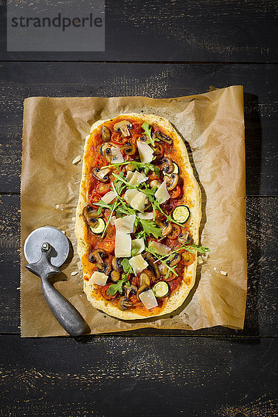Hausgemachte Pizza mit Champignons  Rucola  Zucchini  Tomaten und Parmesan