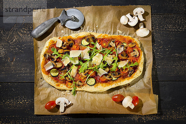 Hausgemachte Pizza mit Champignons  Rucola  Zucchini  Tomaten und Parmesan