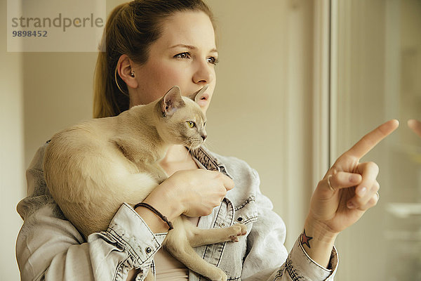 Frau mit burmesischer Katze am Fenster