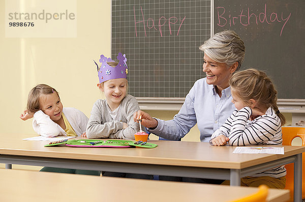 Lehrerin und Schülerinnen feiern Geburtstag im Klassenzimmer