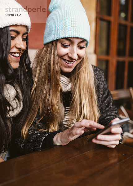 Zwei junge Frauen  die mit dem Smartphone eine Nachricht senden