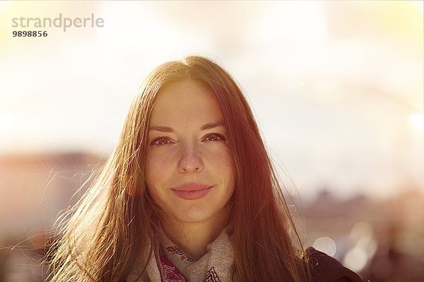 Porträt einer lächelnden jungen Frau im Gegenlicht