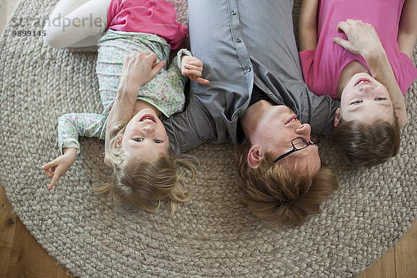 Vater mit zwei Töchtern auf dem Boden liegend