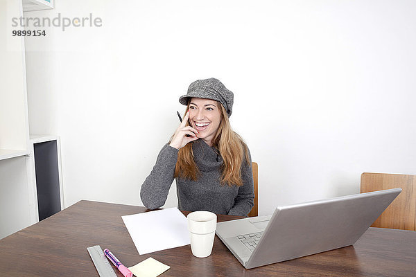 Porträt einer lächelnden Frau mit Laptop am Holztisch