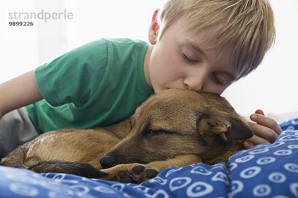Junge und Hund kuscheln auf dem Bett