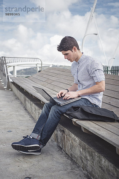 Spanien  Ferrol  junger Mann mit einem Laptop im Freien