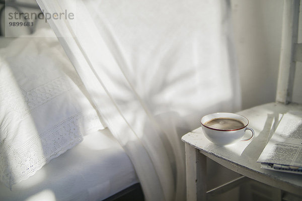 Tasse Kaffee und Zeitung auf einem alten Stuhl im Schlafzimmer