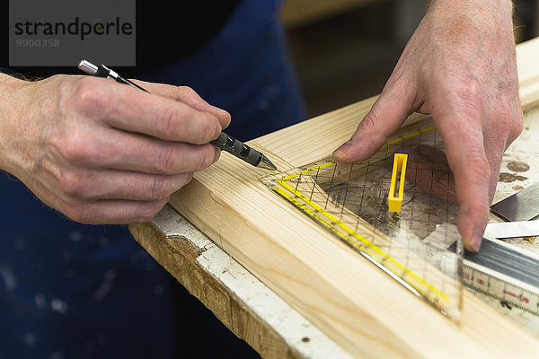 Rahmenbauer in der Werkstatt beim Markieren eines Holzrahmens