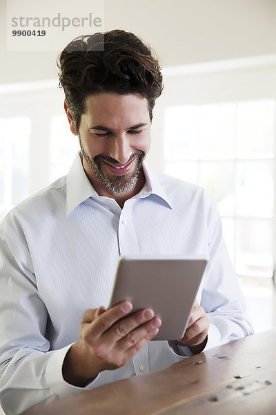 Reifer Mann zu Hause  mit digitalem Tablett