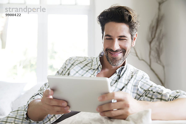 Reifer Mann zu Hause  mit digitalem Tablett