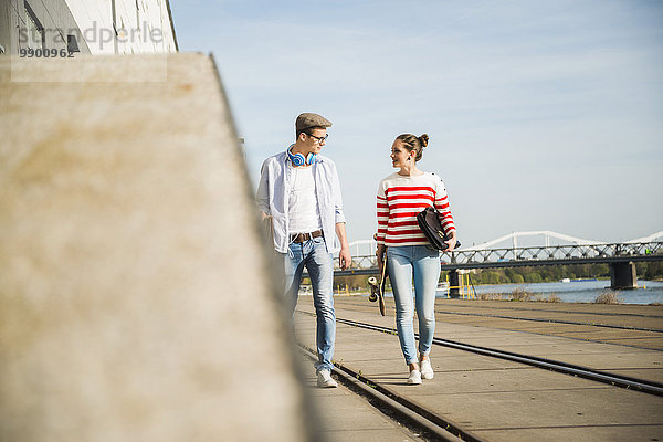 Junger Mann und junge Frau  die am Flussufer spazieren gehen