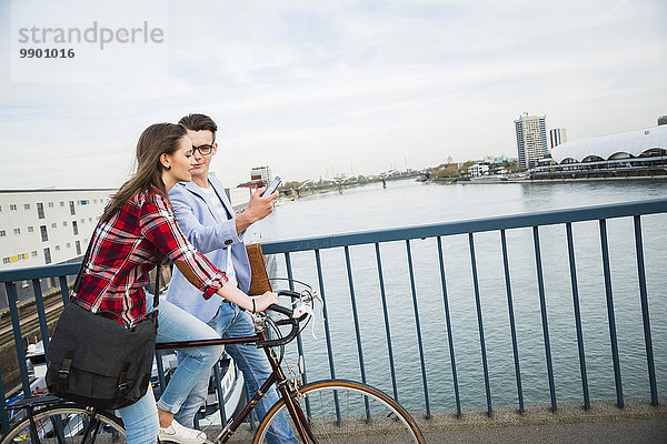 Deutschland  Mannheim  junger Mann und Frau mit Fahrrad und Handy auf Brücke