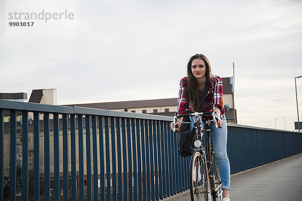 Junge Frau beim Radfahren auf der Brücke
