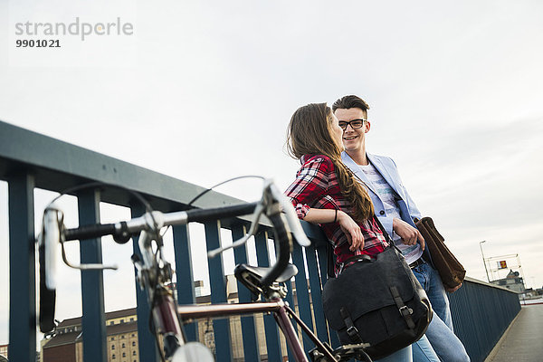 Junger Mann und Frau mit Fahrrad auf Brücke