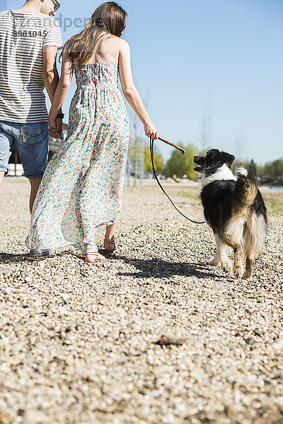 Junges Paar  das im Sommer mit Hund im Freien spazieren geht