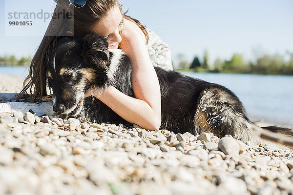 Deutschland  Mannheim  junge Frau kuschelt mit Hund am Rhein