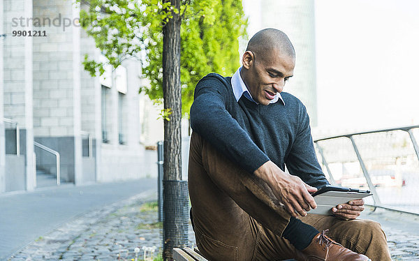 Mann auf der Bank sitzend mit digitalem Tablett