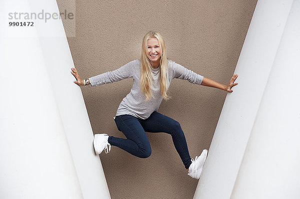 Porträt einer lächelnden blonden Teenagerin zwischen Betonsäulen