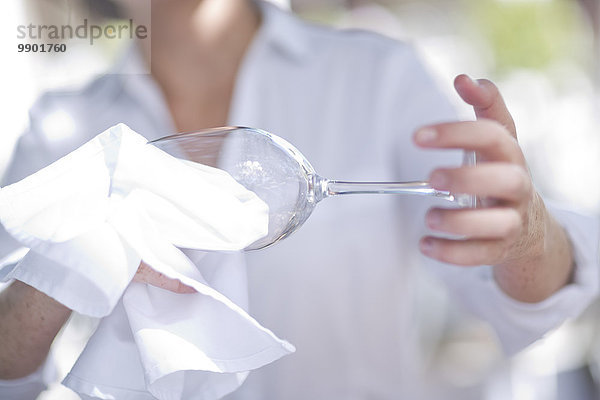 Kellnerin beim Reinigen eines Weinglases mit einem Tuch