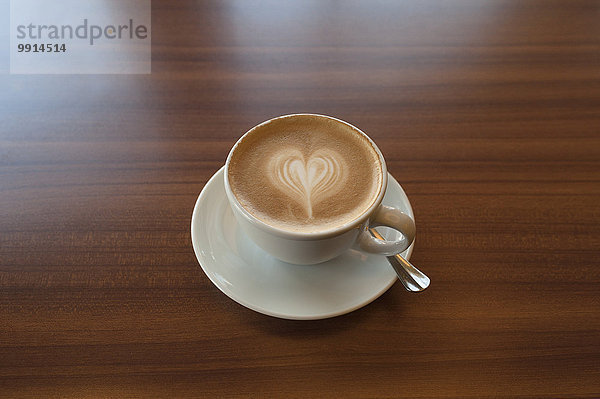 Cappuccino mit Herz auf einem Holztisch