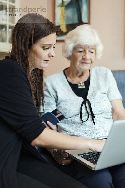 Großmutter und Enkelin mit Laptop zu Hause