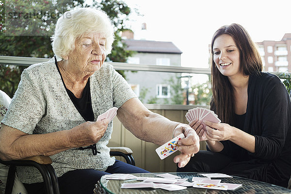 Großmutter und Enkelin beim Kartenspiel auf der Veranda