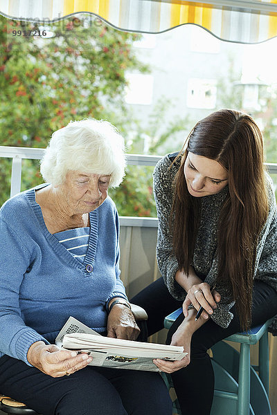 Großmutter und Enkelin beim Zeitungslesen auf der Veranda