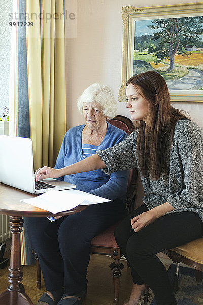 Großmutter und Enkelin nutzen gemeinsam den Laptop zu Hause