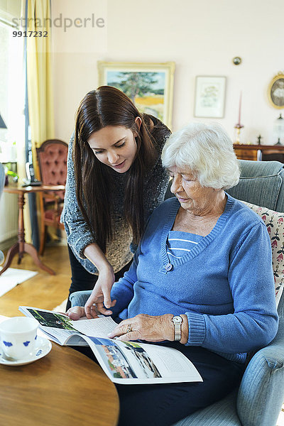 Großmutter und Enkelin lesen zusammen im Wohnzimmer