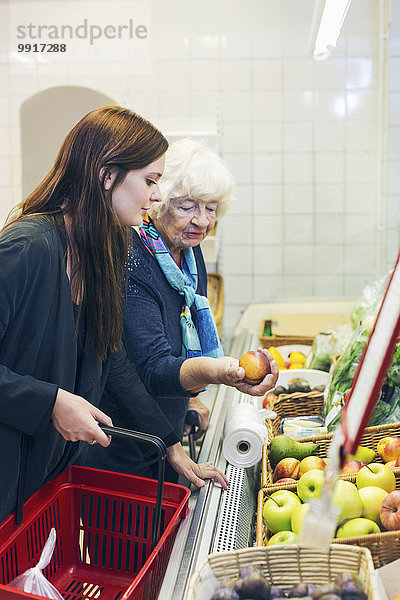 Großmutter und Enkelin beim Obstkauf im Supermarkt