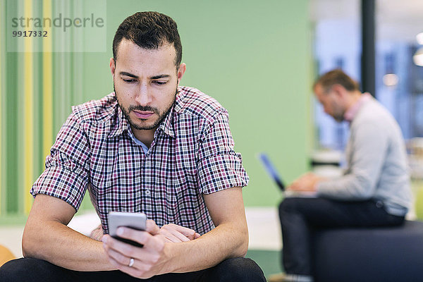 Geschäftsleute  die Technologien in der Lobby im modernen Büro einsetzen