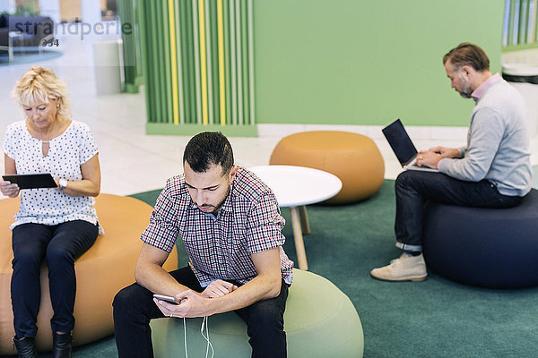 Geschäftsleute  die Technologien in der Lobby im modernen Büro nutzen