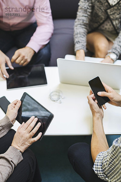 Mittelteil der Geschäftsleute  die Technologien am Tisch im Büro einsetzen