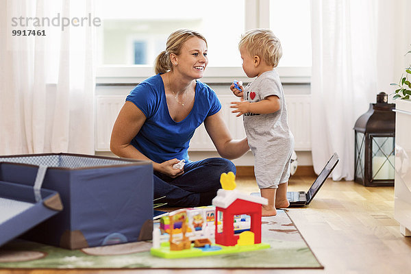 Glückliche Mutter spielt mit dem kleinen Jungen zu Hause.