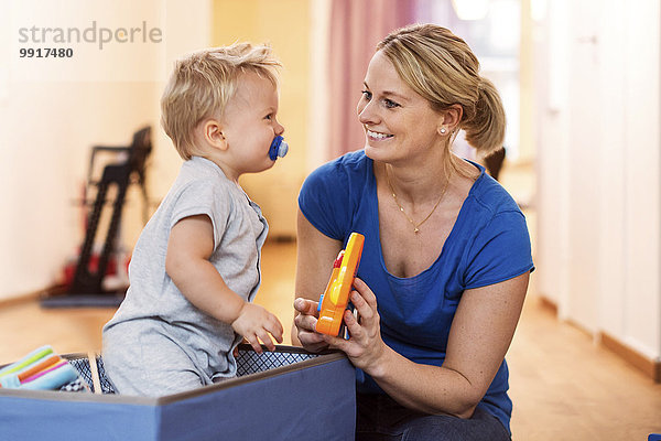 Glückliche Frau spielt Spielzeug mit dem kleinen Jungen zu Hause