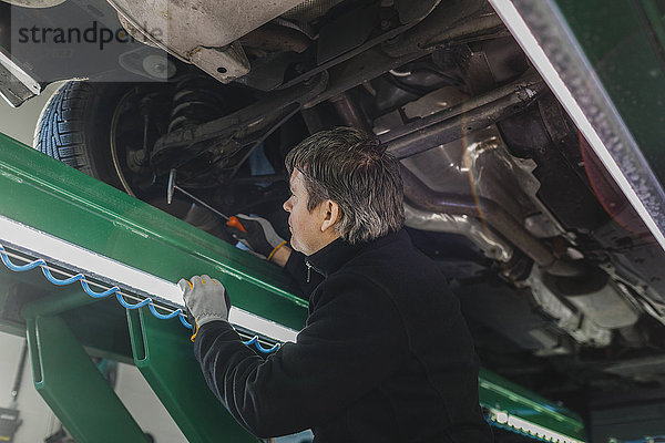 Seitenansicht des Mechaniker-Prüfwagens mit Hammer in der Autowerkstatt