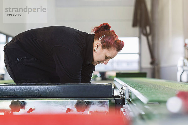 Seitenansicht der Mechanikerin mit hydraulischem Aufzug in der Kfz-Werkstatt